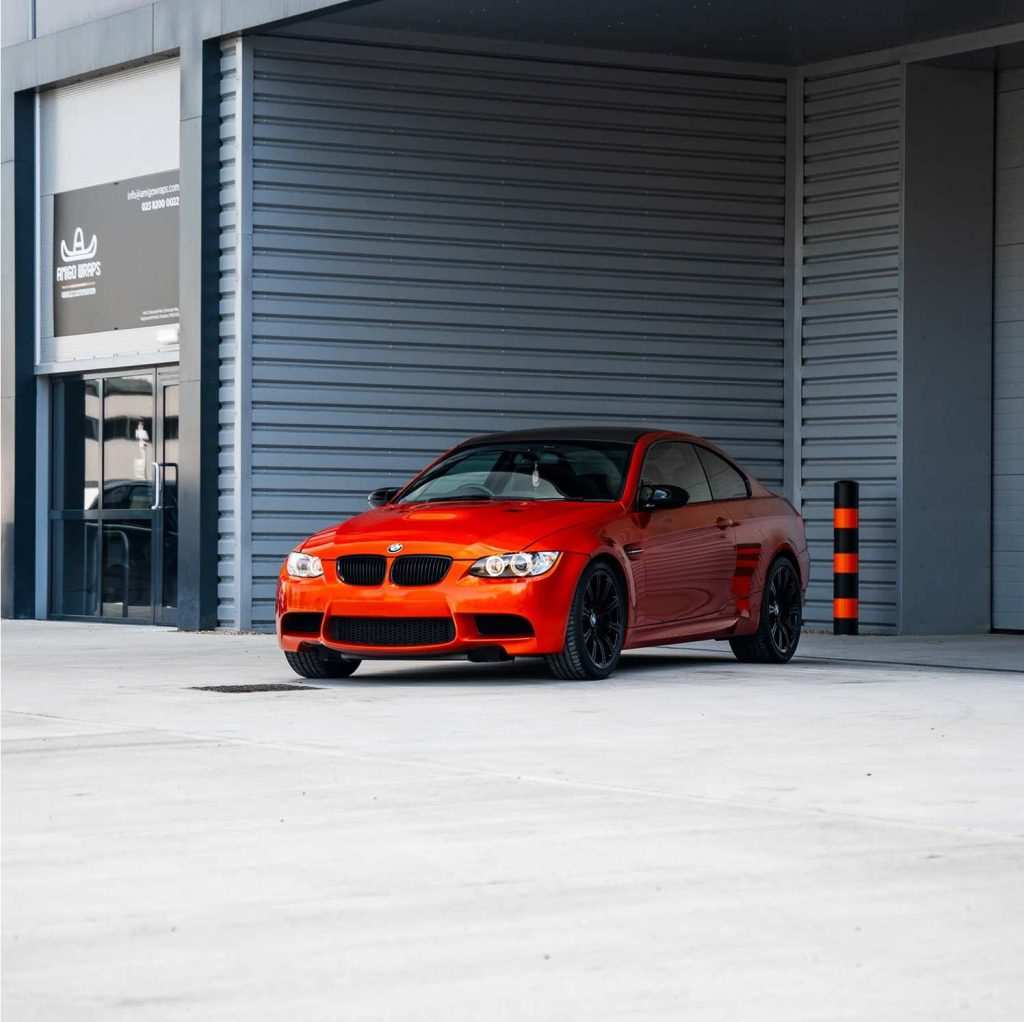 vibrant red car wrap on a car coming out of a garage